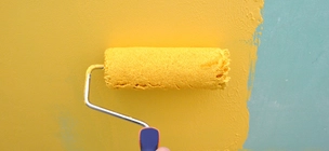 Festőhengerrel való festés sárga festékkel kék falra
