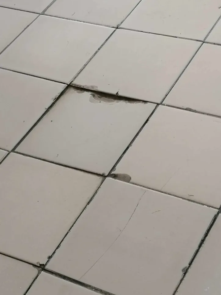 Cracked floor tiles (11444) Cracked and uneven floor tiles indicating possible subfloor issues, requiring inspection and repair.