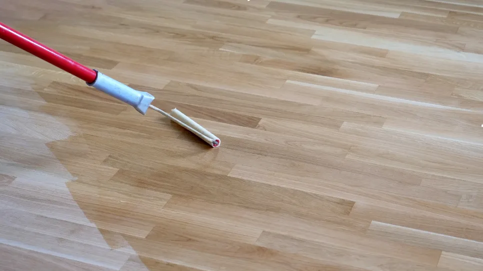 Lakkozott fapadló Fa padló lakkozása folyamatban egy festőhengerrel, a felület védelme és fényesítése érdekében.