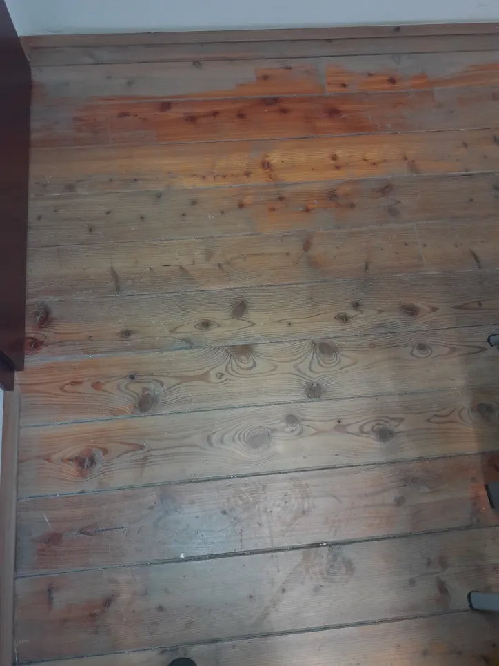 Fa padló látható vízkárral és elszíneződéssel, sötét foltokkal.